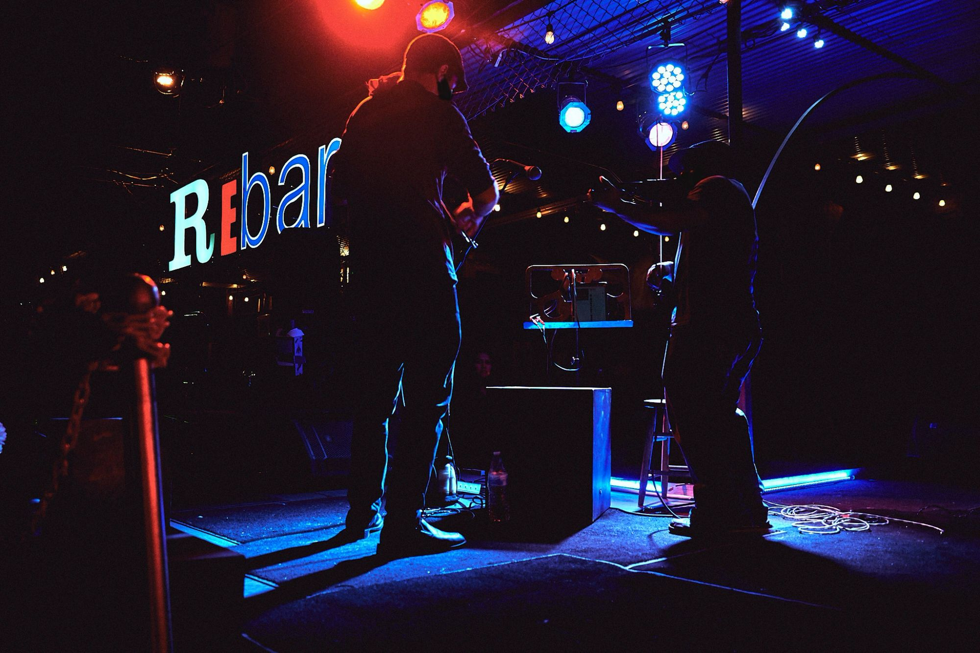 A band playing on ReBAR's patio stage under blue lights.