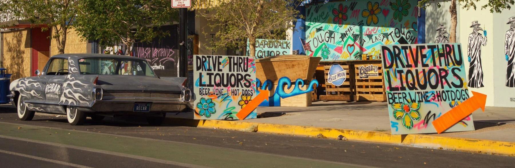 The hand-painted Drive Thru Liquors signs and ReBAR's lowrider on the 18b strip in daylight.